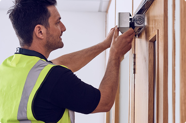 Worker installing door lock using screwdriver