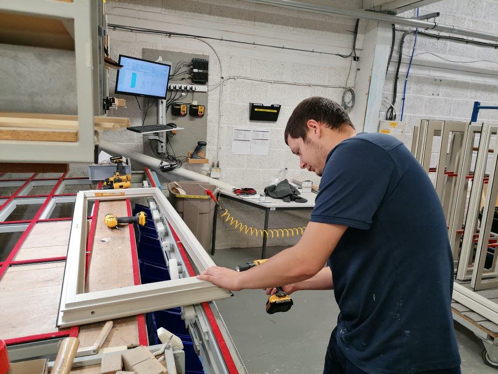 Man measuring timber in a joinery workshop