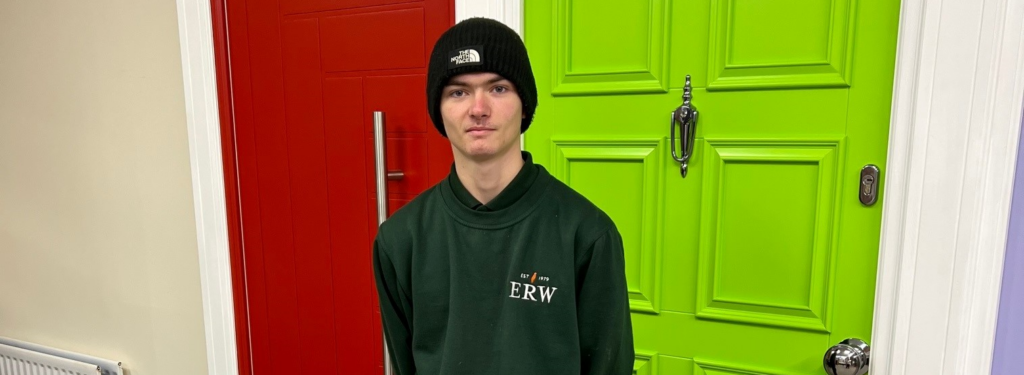 Worker in green hoodie standing in front of a bright green wall