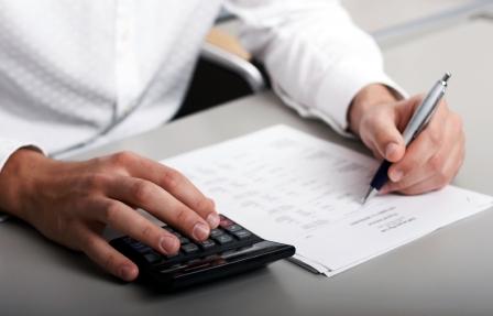 Person typing on a keyboard with pen and notebook beside them