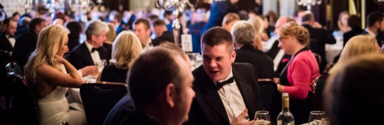 People in suits seated at formal dinner
