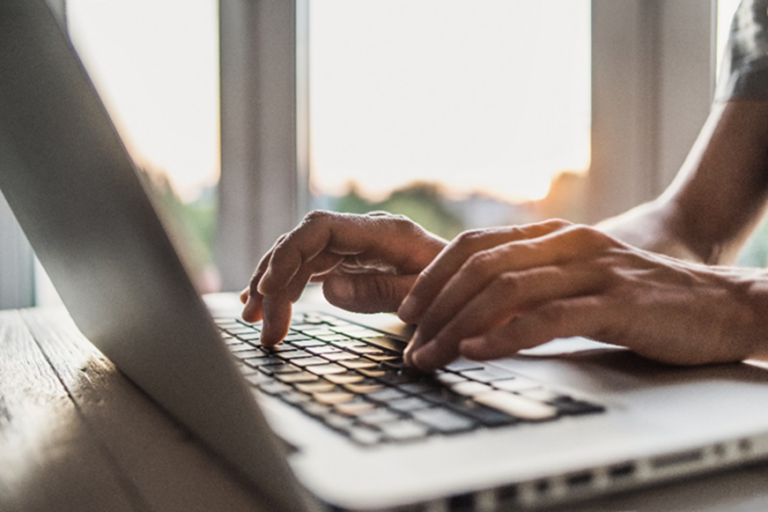 Hands typing on laptop keyboard