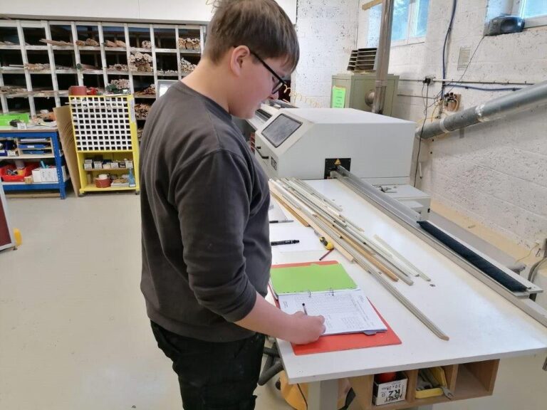 A young man making notes in a ledger in front of machinery