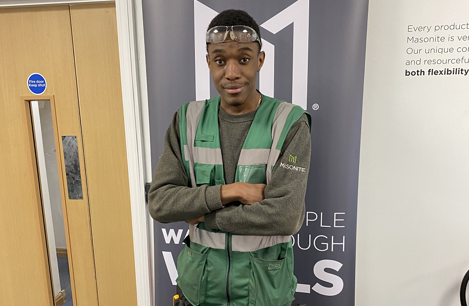 Male student in black jumper posing in a workshop