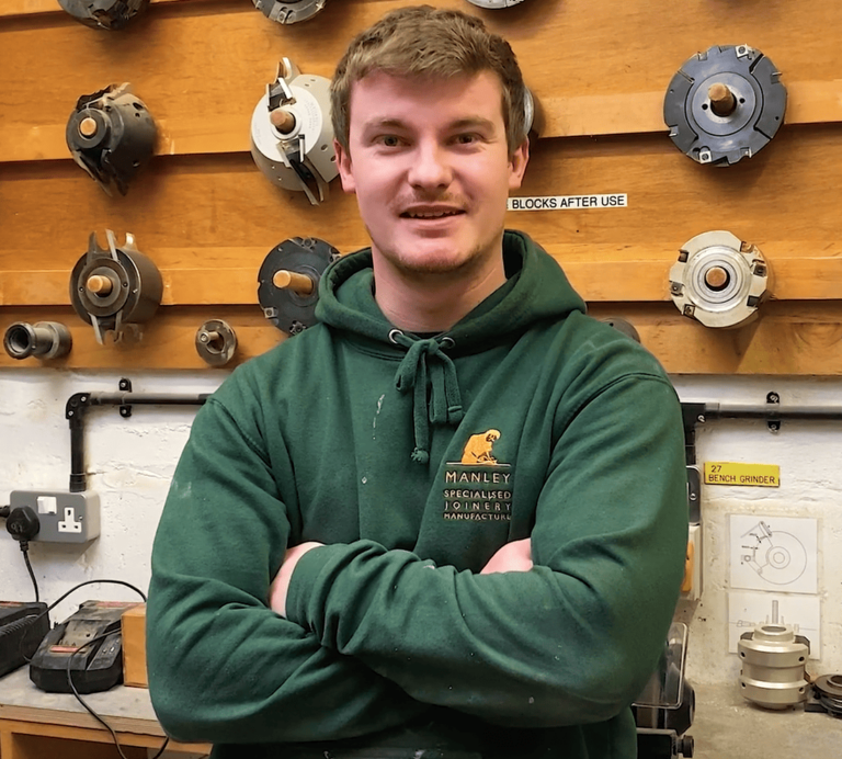 Young man in green hoodie standing in a workshop