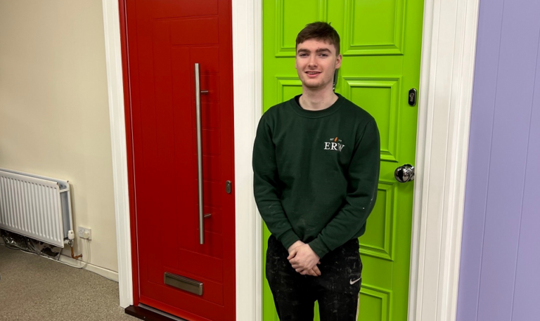 Young man in green uniform standing in front of a bright green door