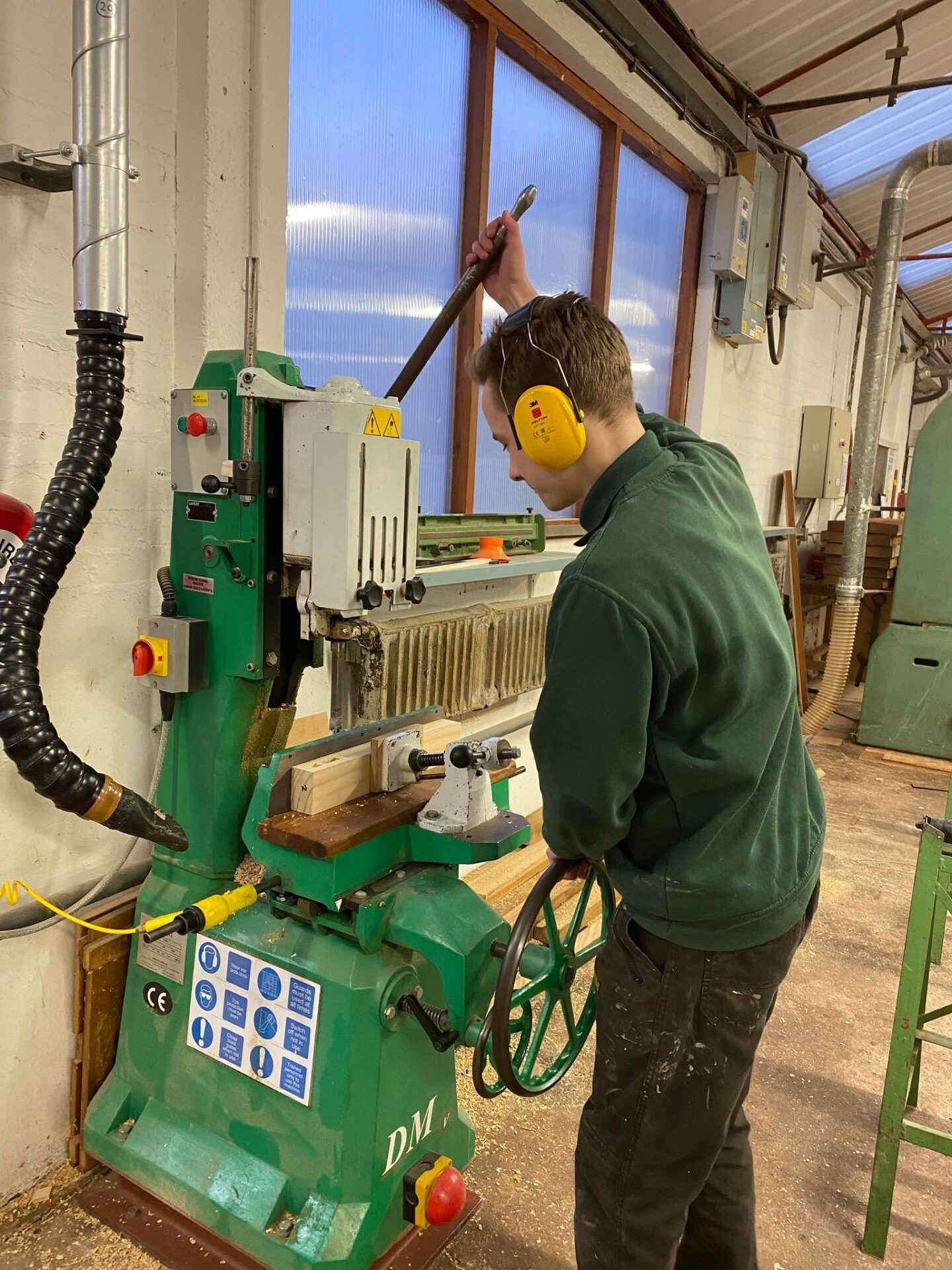 Apprentice using a green industrial woodworking machine