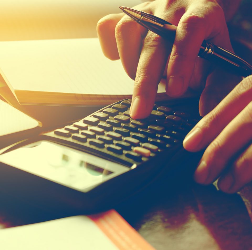 Person typing on calculator next to financial documents