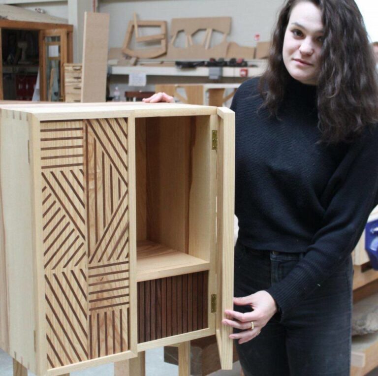 Female student sanding a wooden cabinet