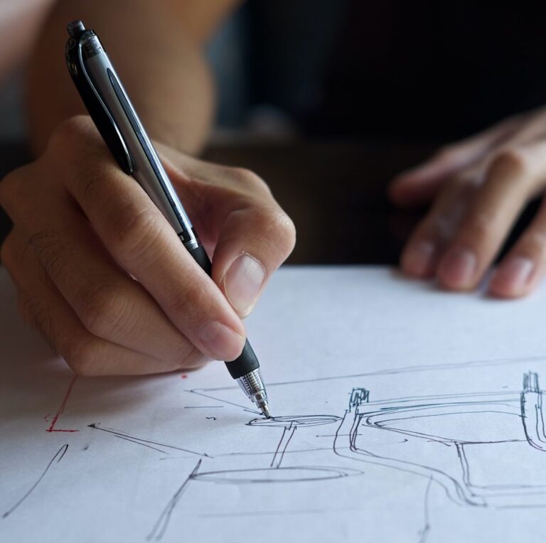 A hand holding a pen drawing a sketch