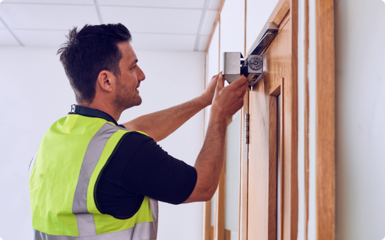 A man working on the closing mechanism of a fire door